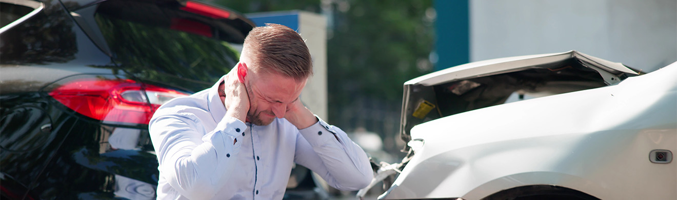 Junger Mann am Auto nach Unfall sucht rechtliche Unterstützung bei Auslandsunfall Anwalt in Kiel.