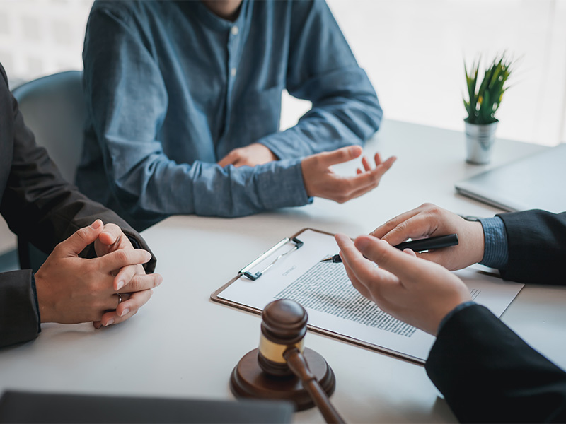 Geschäftspersonen und Anwalt unterschreiben Vertrag über rechtliche Unterstützung, um Auslandsunfall in Kiel professionell zu regulieren. 