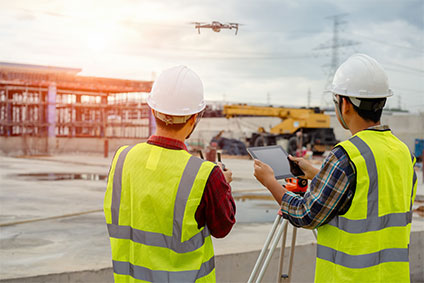 Drohne vom Bauarbeiter auf der Baustelle betrieben, mit Drohne fliegen.