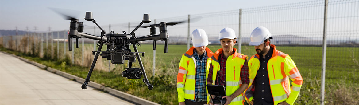 Drei Männer in Warnweste fliegen eine Drone.