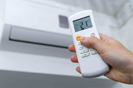 Klimaanlage in einem Raum bedienbar mit einer Fernbedienung. Reguliert die Temperatur und kühlt die Luft im Raum.